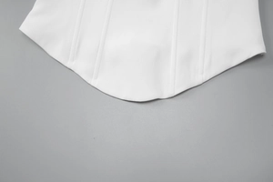 Detail view of the white dress curved hemline with vertical stitching and zip closure