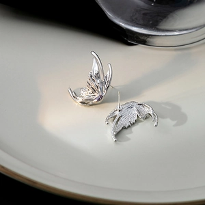 Irregular liquid metal butterfly wing earrings with purple crystal in white porcelain dish
