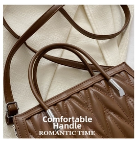 Detail of dark brown V-quilted faux leather handbag with round handles and silver hardware