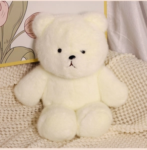 Close-up of a soft white teddy bear plush toy sitting on a cozy knitted blanket
