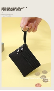 Détail d'un petit porte-monnaie noir en tissu avec trois fermetures éclair et anneau métal