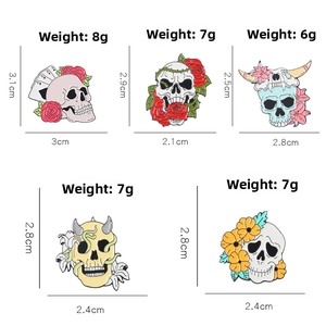 Detailed view of colorful enamel skull pins with floral patterns and distinct weights