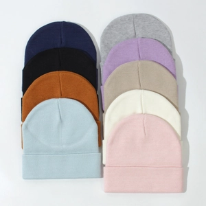 Flat lay showing nine colorful knitted beanies for babies in a variety of solid colors