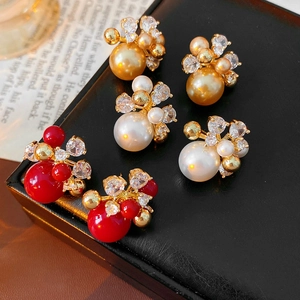 Close-up of vintage gold-plated pearl and zircon earrings arranged on a black leather box