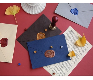 Macro shot of vintage linen textured envelopes with wax seal stamps and brass tools