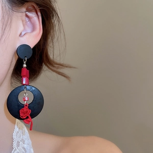 Détail de boucles d'oreilles rétro avec pendentif rose rouge et anneaux en bois noir