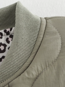 Detailed view of the ribbed collar and quilted olive green jacket with leopard print lining