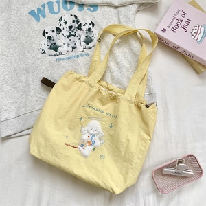 Macro detail of yellow canvas tote bag featuring delicate cartoon embroidery and drawstring