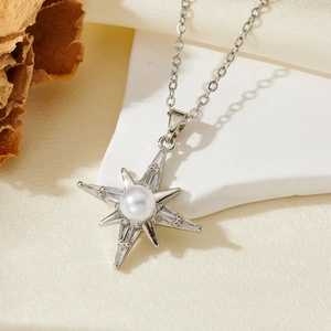 Close-up of silver starburst necklace with a central pearl and sparkling zircon accents