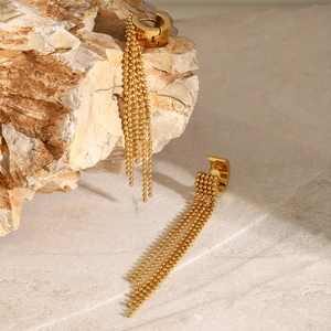 Detail shot of golden bead chain tassel earrings on a natural stone surface