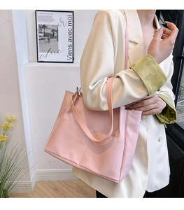 Dettaglio della borsa tote rosa in pelle con tasca frontale e modella in blazer