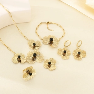 Detail of gold flower jewelry set with brushed petals and black bead center on silk