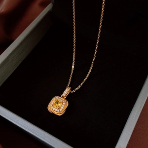 Macro view of vintage gold necklace featuring a square pendant with yellow gemstone and diamonds