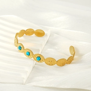Gros plan du bracelet en acier inoxydable doré orné de trois pierres turquoises