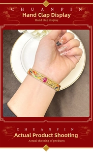 Dettaglio di un bracciale dorato in stile cinese con smalti e pietra preziosa incastonata