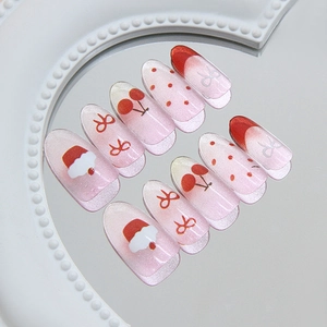 Pink gradient cat eye press-on nails with red bows, cherries, and festive holiday designs