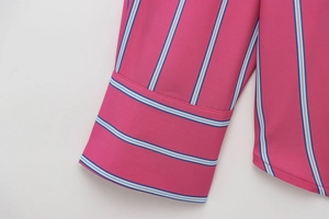 Detail of rose pink shirt cuff with blue and white striped contrast stitching