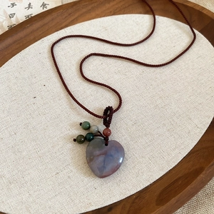 Detail of heart-shaped natural agate pendant with woven rope and colorful beads
