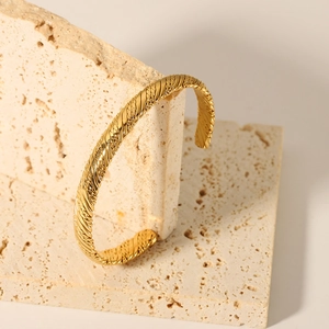 Detail showing gold irregular braided texture on the stainless steel C-shaped cuff bracelet