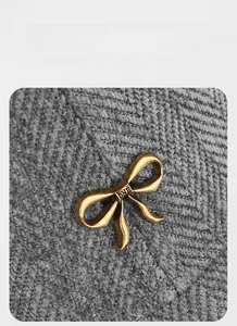 Détail macro d'un nœud métallique doré vintage avec gravure DNB sur textile gris