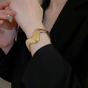 Minimalist gold wavy irregular open cuff bracelet and matching ring set on a model
