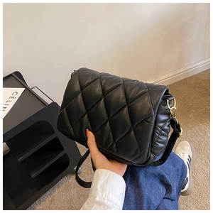 Detailed close-up of a black quilted crossbody bag with gold hardware and leather strap