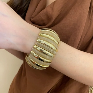 Macro shot of a chunky elastic bracelet with gold metal and beige resin segments