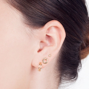 Minimalist gold sunflower and starburst earring set with small studs and a hoop on ear