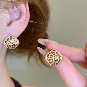 Detailed close-up of square leopard print earrings with gold metal edges on model