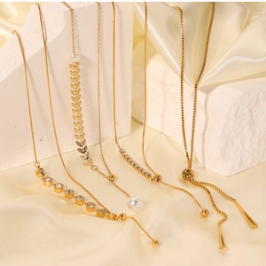 Detail of gold-plated necklaces with pearls and zircons on white stone and silk texture