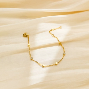 Gros plan du bracelet en titane doré avec disques polis et détails en zircon scintillants