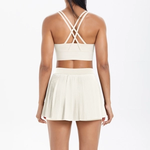 Detail of cross-back yoga bra and high-waisted pleated tennis skirt in off-white