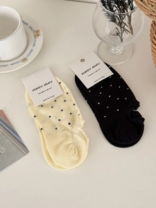 Gros plan de chaussettes basses à pois en coton beige et noir sur un bureau décoré
