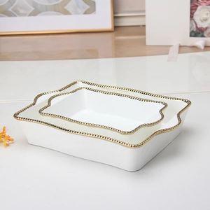 Detail shot of the white ceramic square plate featuring elegant gold rim and beaded texture