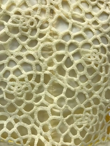 Gros plan sur la broderie florale en dentelle jaune clair et les détails du mesh