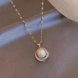 Detail of a gold necklace with interlocking rings, a pearl pendant and rhinestones