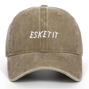 Detail shot of white ESKETIT letter embroidery on a washed khaki vintage baseball cap