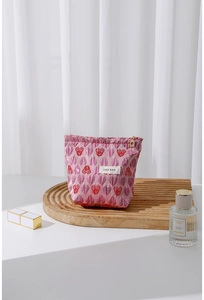 Close-up of pink heart jacquard makeup bag with H&R BAG logo on wooden display stand