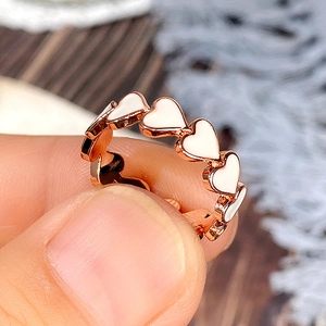 Détail d'une bague coeur en or rose avec incrustation d'émail blanc et métal poli