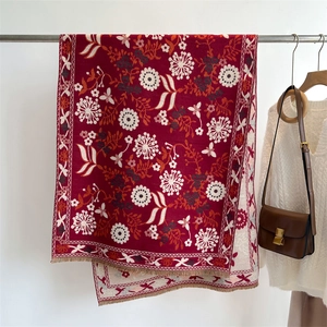Detail of red floral knit scarf with tassels and thick faux cashmere fabric texture
