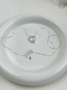 Detail view of a 925 sterling silver heart shell pendant on a thin snake chain necklace