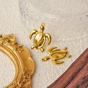 Golden sea turtle pendants made of 304 stainless steel on a beige textured background