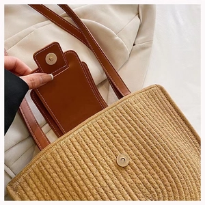 Detail view of the brown woven straw bag with a matching leather card holder and magnetic clasp