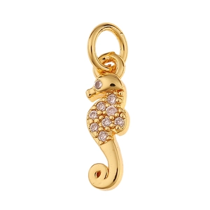 Detail van een gouden zeepaardje hanger met sprankelende kristallen en een bovenste ring