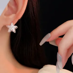 Silver star earrings with cubic zirconia inlay worn by model against black background