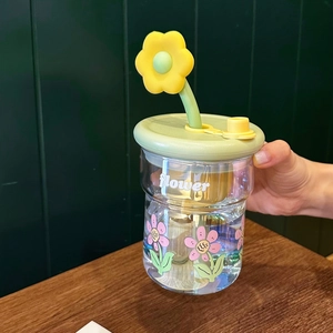 Détail du verre à motif floral avec couvercle vert et paille ornée d'une petite fleur