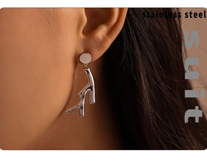 Macro view of silver tree branch earrings in polished stainless steel on a model