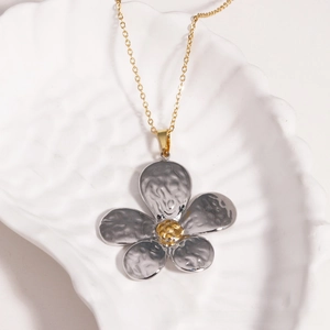 Détail du pendentif pétale argenté à texture martelée et centre doré sur chaîne