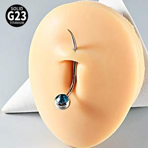Detail of G23 titanium curved barbell body piercing with blue gem on silicone model