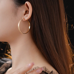 Nahaufnahme goldener strukturierter Creolen mit metallischem Glanz und elegantem Stil